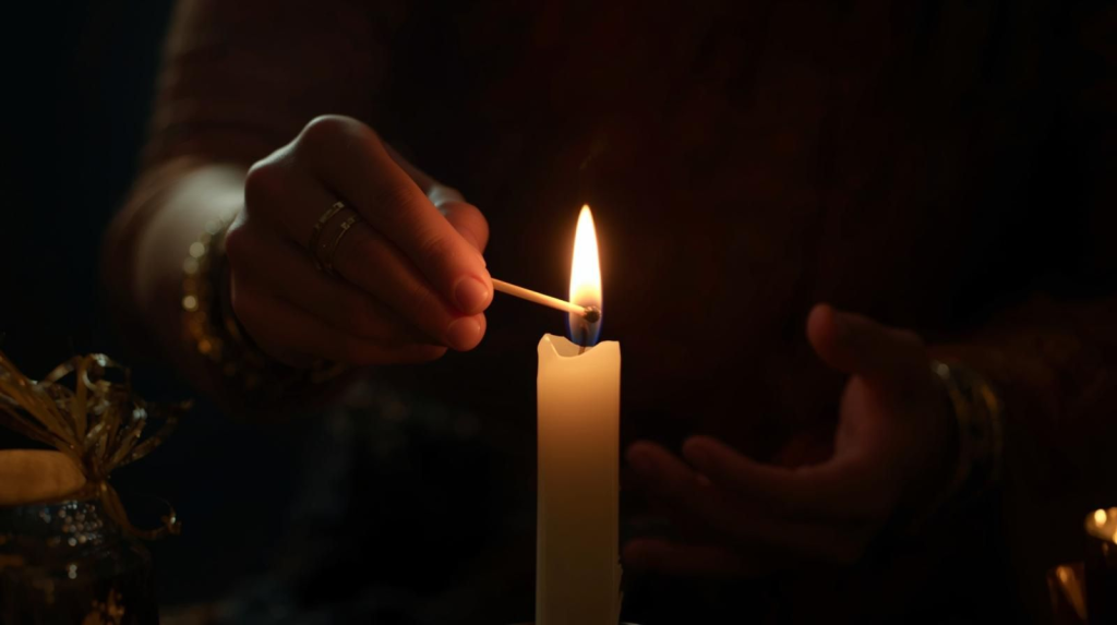 Hands lighting a candle during a full moon ceremony, symbolizing intention setting and spiritual focus.