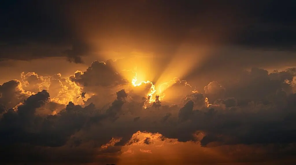 10 Signs of Spiritual Protection You're Already Experiencing Sunlight piercing through dark clouds in a dramatic sky at sunset.